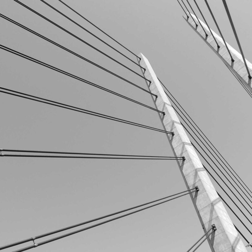 Black and white view looking upwards of suspension bridge towers to represent Civil Engineering Industry and Industries.